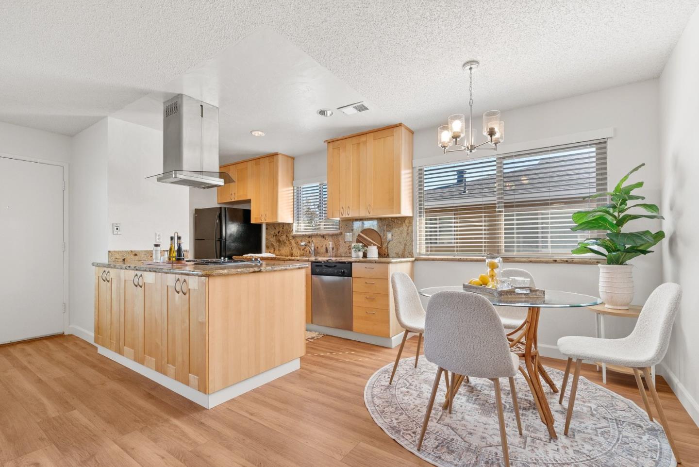 4465 Diamond Street, Unit 4 Capitola, CA 95010 - Photo 12 of 41 a kitchen with stainless steel appliances kitchen island granite countertop a table chairs in it and wooden floors