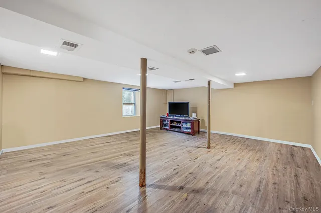 a view of empty room with wooden floor and flat screen tv