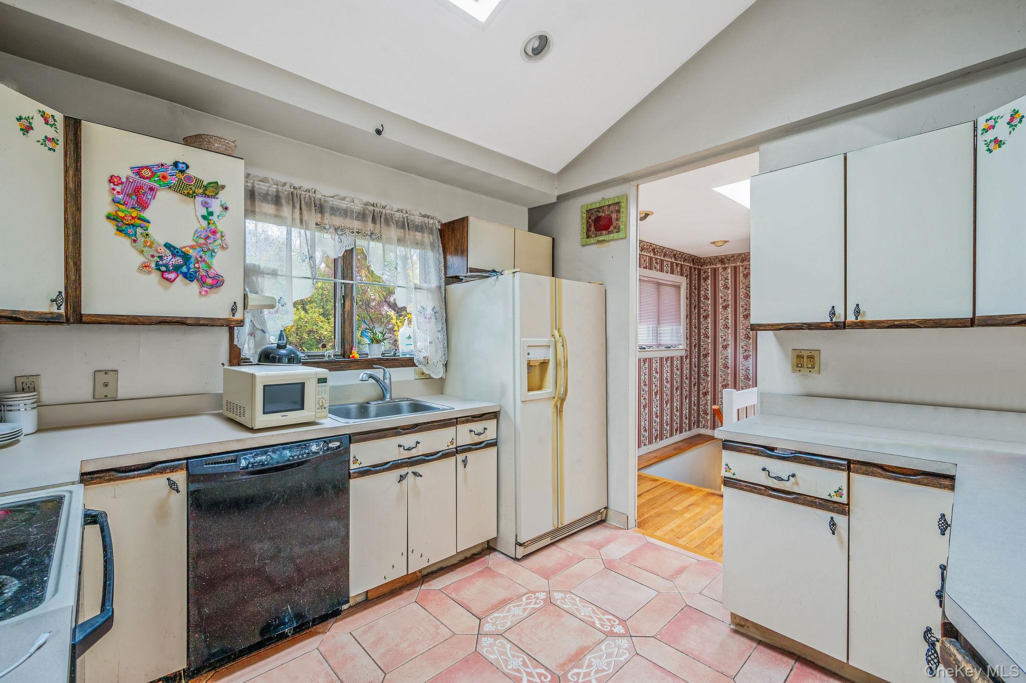 194 Central Park Road Plainview, NY 11803 - Photo 7 of 19 Kitchen featuring light countertops, white appliances, lofted ceiling, a skylight, and white cabinetry