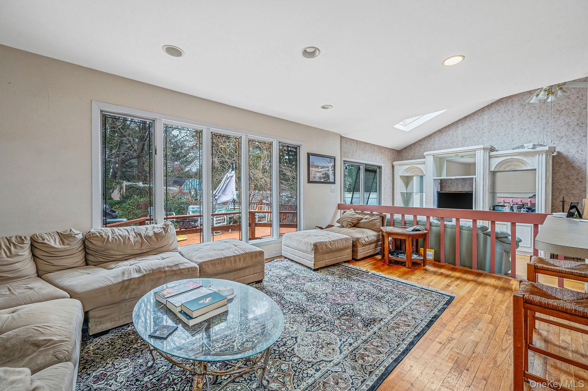 194 Central Park Road Plainview, NY 11803 - Photo 9 of 19 Living area with vaulted ceiling, a skylight, hardwood / wood-style flooring, wallpapered walls, and recessed lighting
