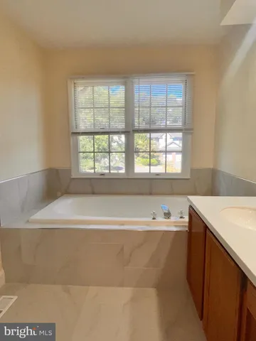 a bathroom with a tub a sink and a window