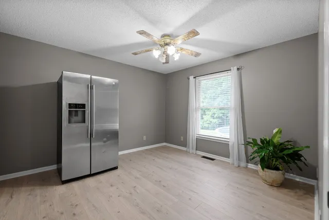 a view of an empty room with window and wooden floor