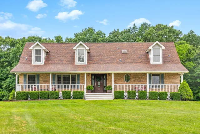 a view of a brick house next to a yard with big trees