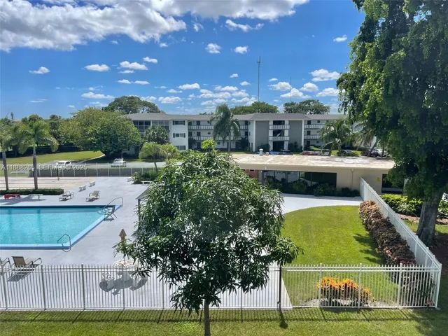 a view of a swimming pool with lawn chairs and plants