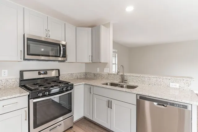 a kitchen with granite countertop white cabinets and stainless steel appliances