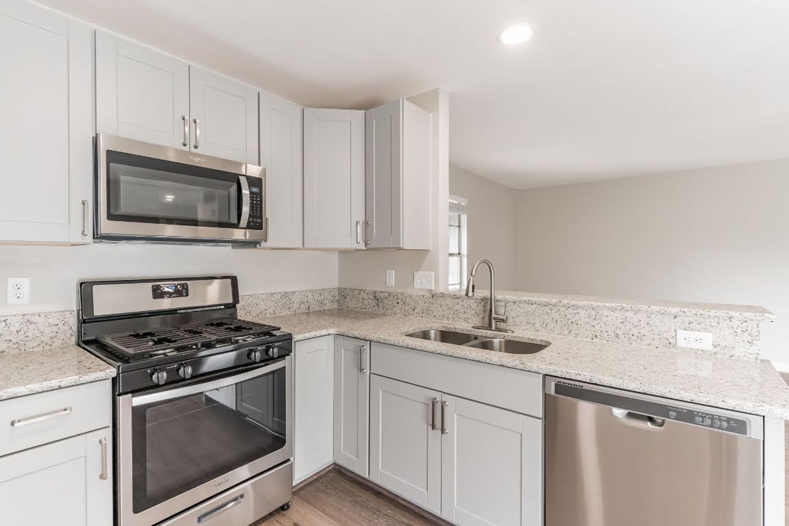 a kitchen with granite countertop white cabinets and stainless steel appliances