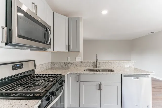 a kitchen with stainless steel appliances granite countertop a sink stove and microwave