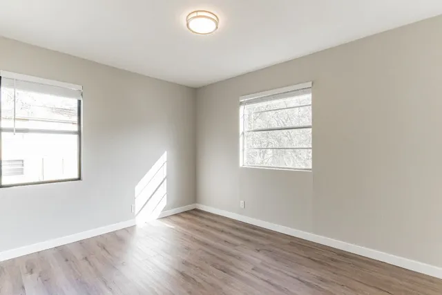 an empty room with wooden floor and windows
