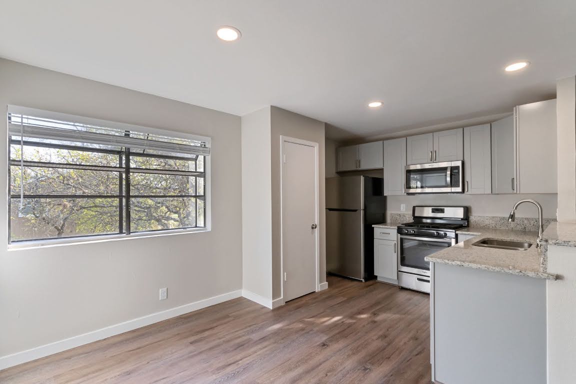 401 Hedgewood Drive, Unit D Georgetown, TX 78628 - Photo 10 of 19 a kitchen with granite countertop stainless steel appliances a stove top oven a refrigerator a sink and a window