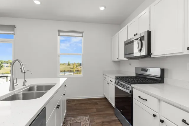 a kitchen with stainless steel appliances granite countertop white cabinets a stove top oven a sink and dishwasher