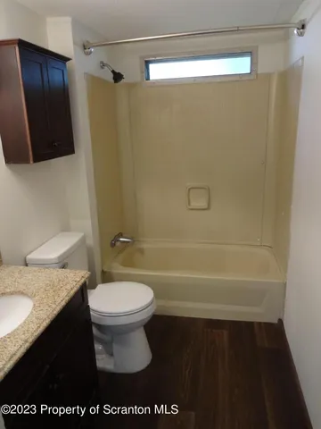 a bathroom with a granite countertop bathtub shower sink vanity and toilet