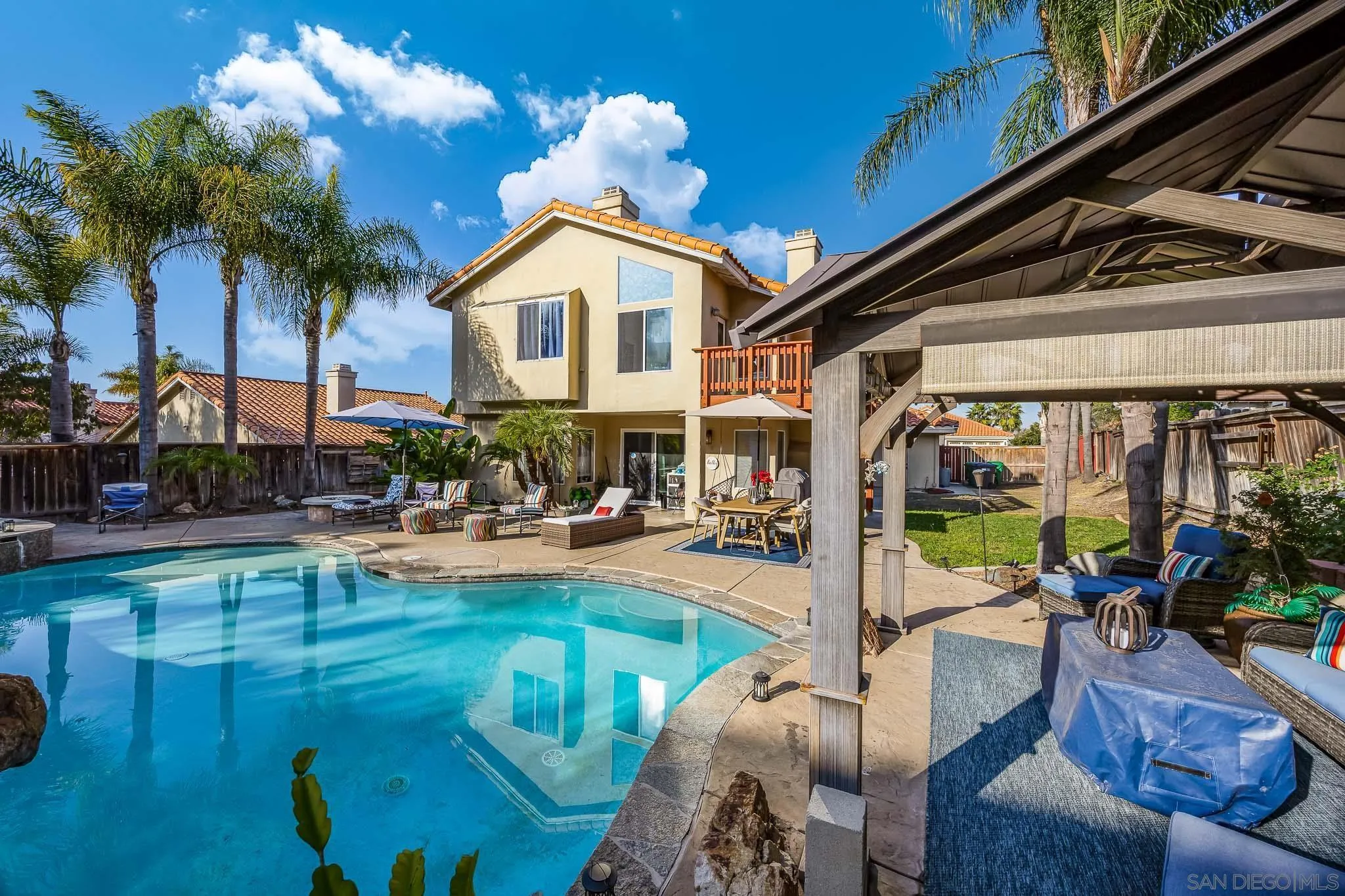 5063 Frazee Road Oceanside, CA 92057 - Photo 38 of 45 a view of a patio with couches table and chairs potted plants and palm trees