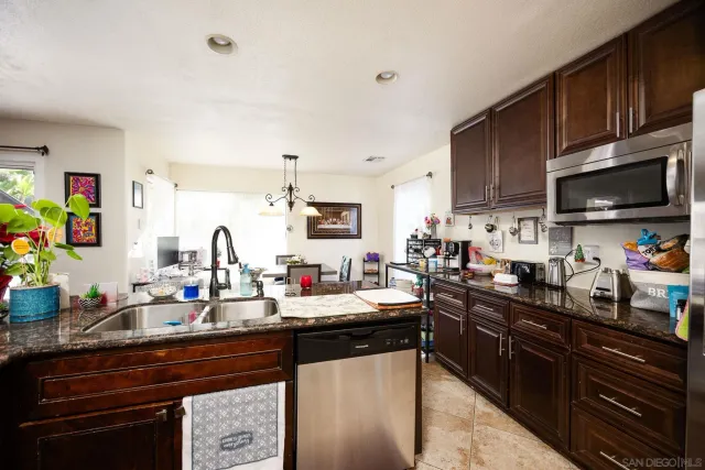 a kitchen with kitchen island granite countertop a sink dishwasher stove and cabinets with wooden floor