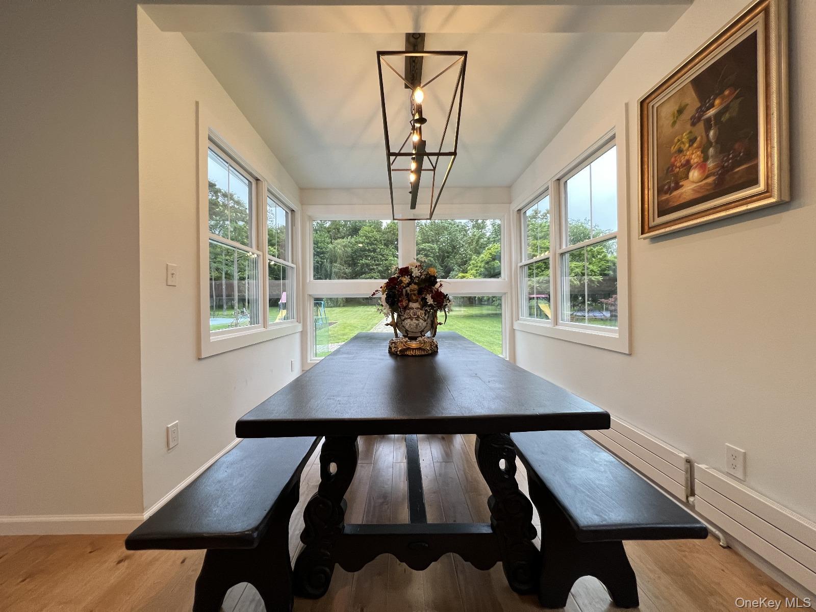 87 Wheatley Road Old Westbury, NY 11568 - Photo 11 of 16 Dining room featuring healthy amount of natural light, light wood-style floors, baseboards, and a chandelier
