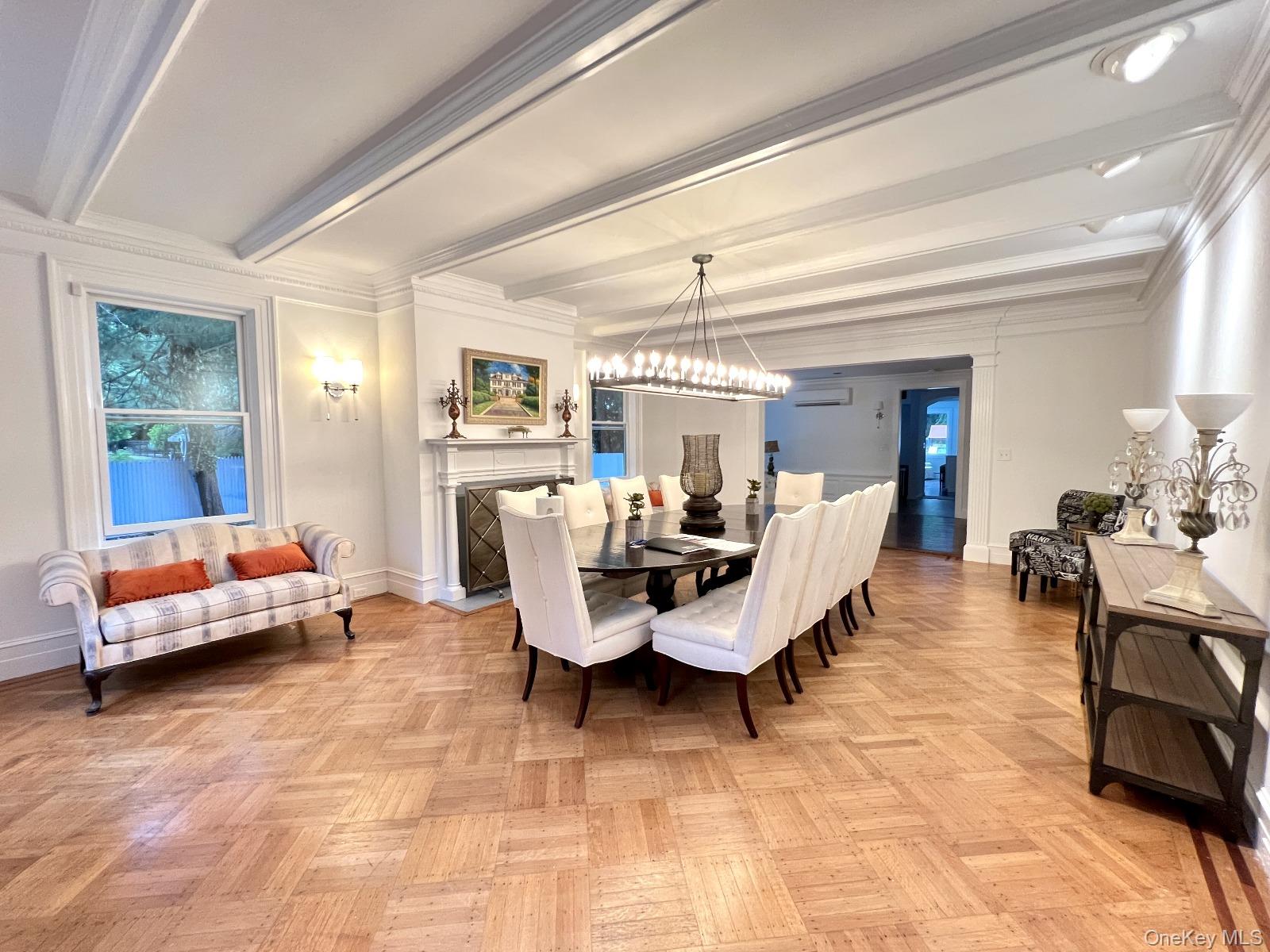 87 Wheatley Road Old Westbury, NY 11568 - Photo 12 of 16 Dining area with beam ceiling, a chandelier, baseboards, a fireplace, and crown molding