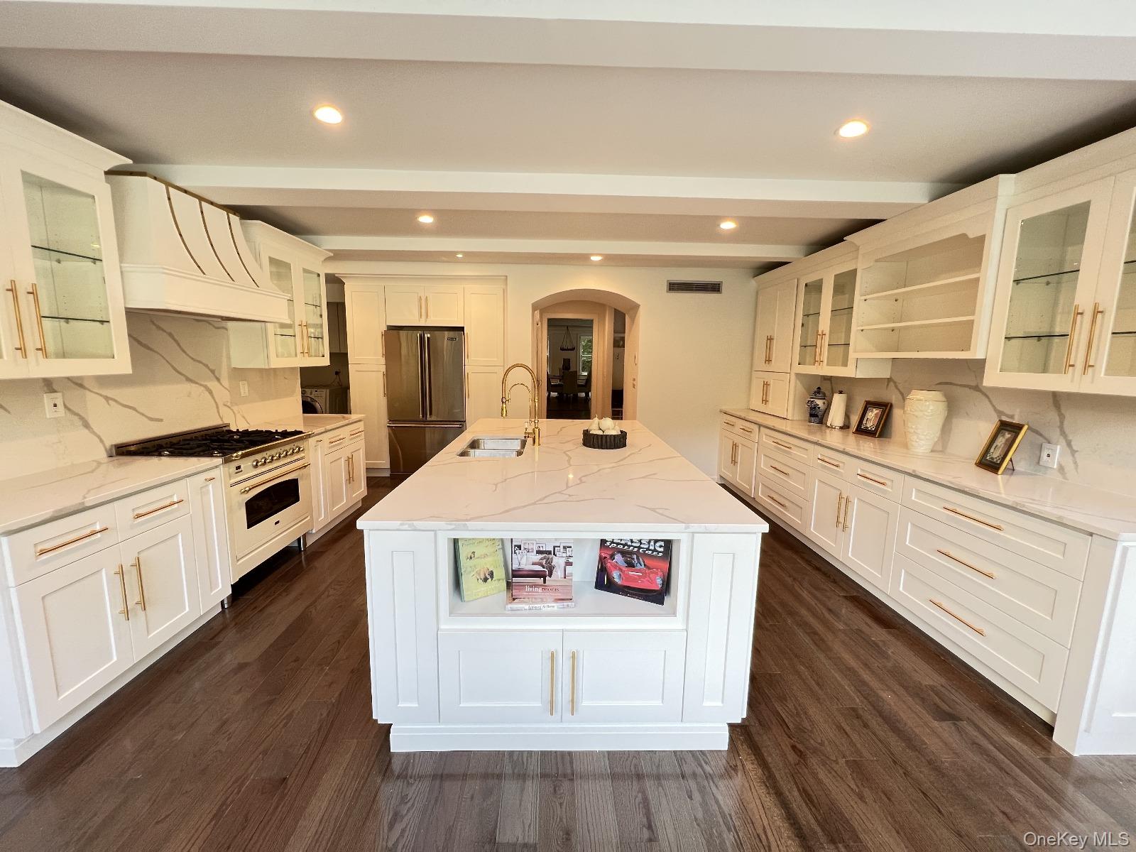 87 Wheatley Road Old Westbury, NY 11568 - Photo 5 of 16 Kitchen with freestanding refrigerator, a sink, premium range hood, arched walkways, and dark wood-style floors