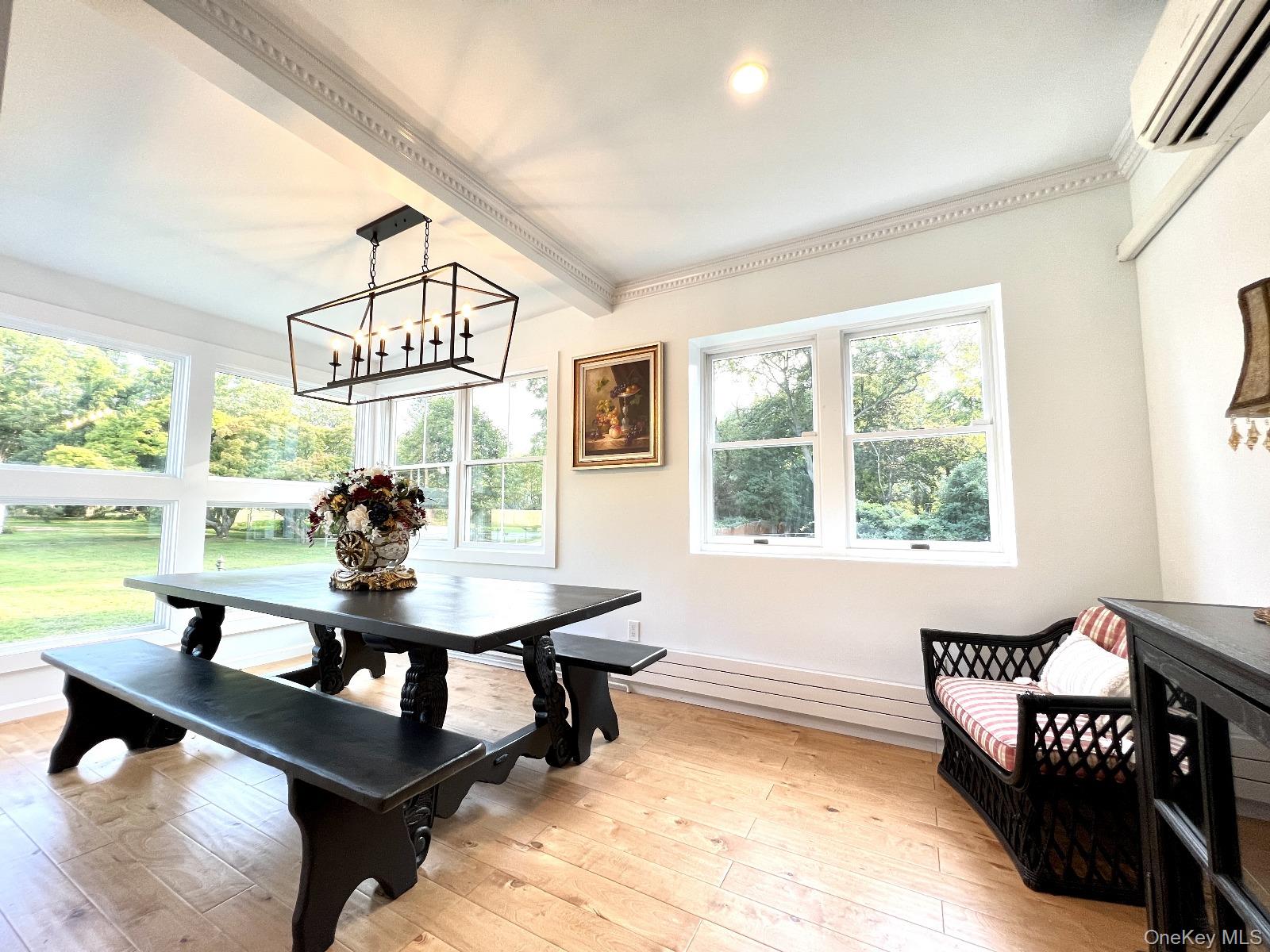 87 Wheatley Road Old Westbury, NY 11568 - Photo 8 of 16 Dining space with a wall mounted AC, light wood finished floors, a chandelier, beam ceiling, and crown molding