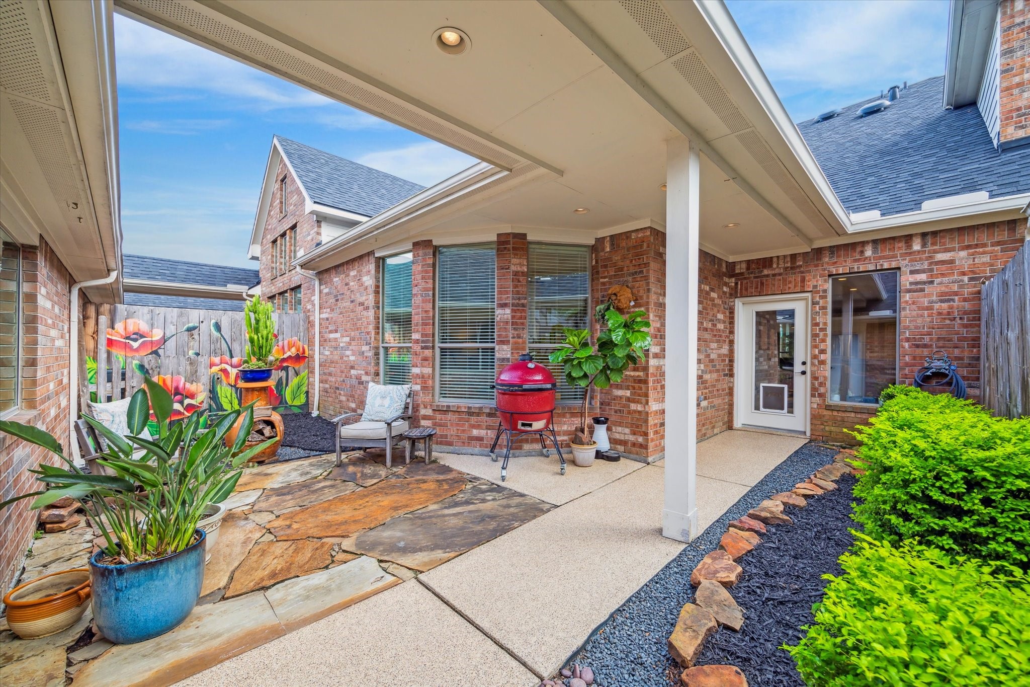 3310 Spring Landing Lane Pearland, TX 77584 - Photo 12 of 32 Low-maintenance back patio space between the home and garage with flagstone, epoxy covered concrete and black star gravel ready for outdoor seating/planters, supported by sprinkler system and drip irrigation.