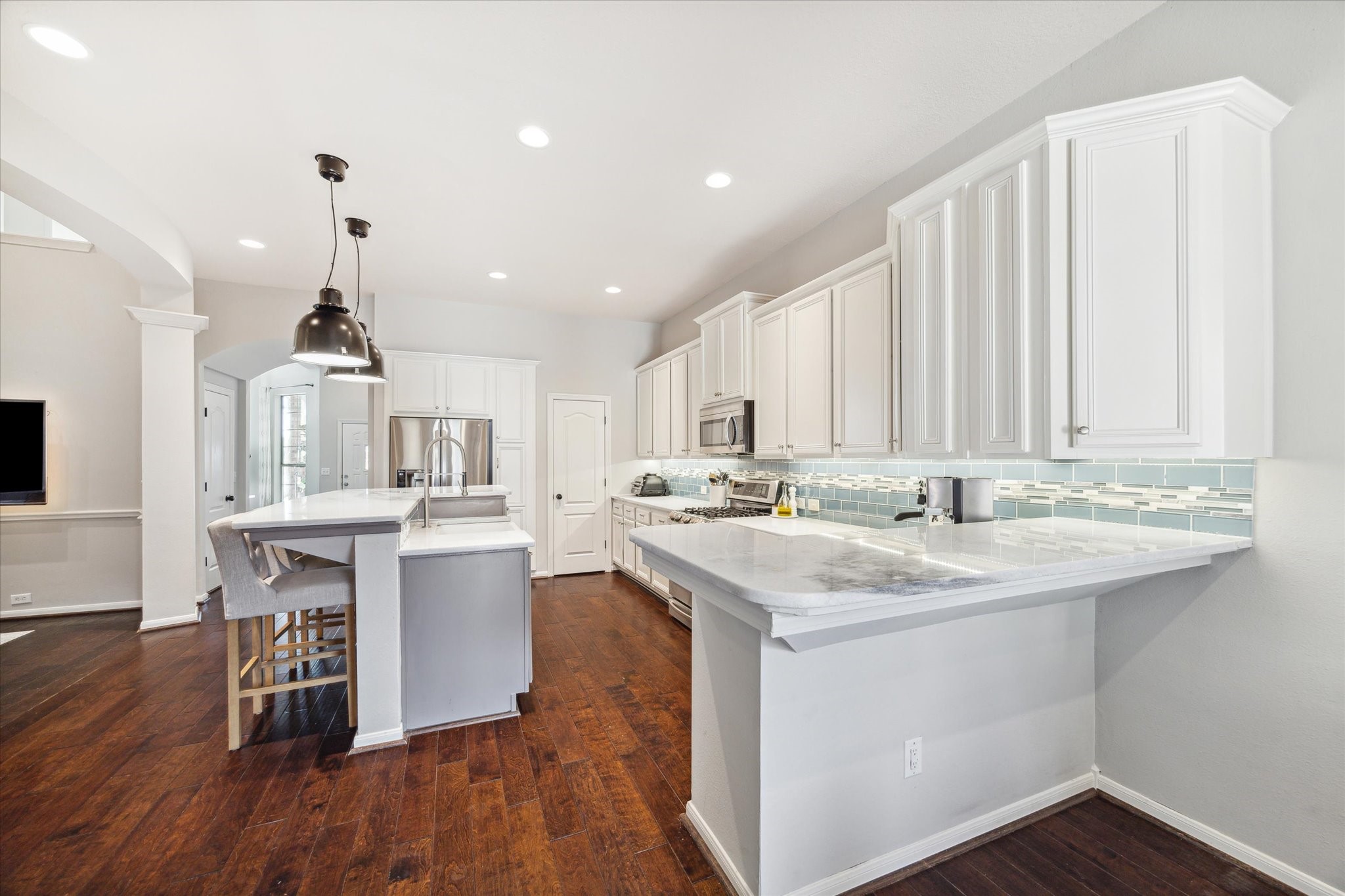 3310 Spring Landing Lane Pearland, TX 77584 - Photo 17 of 32 Another angle highlighting the stone counters and the glass backsplash detail that elevates the remodel.