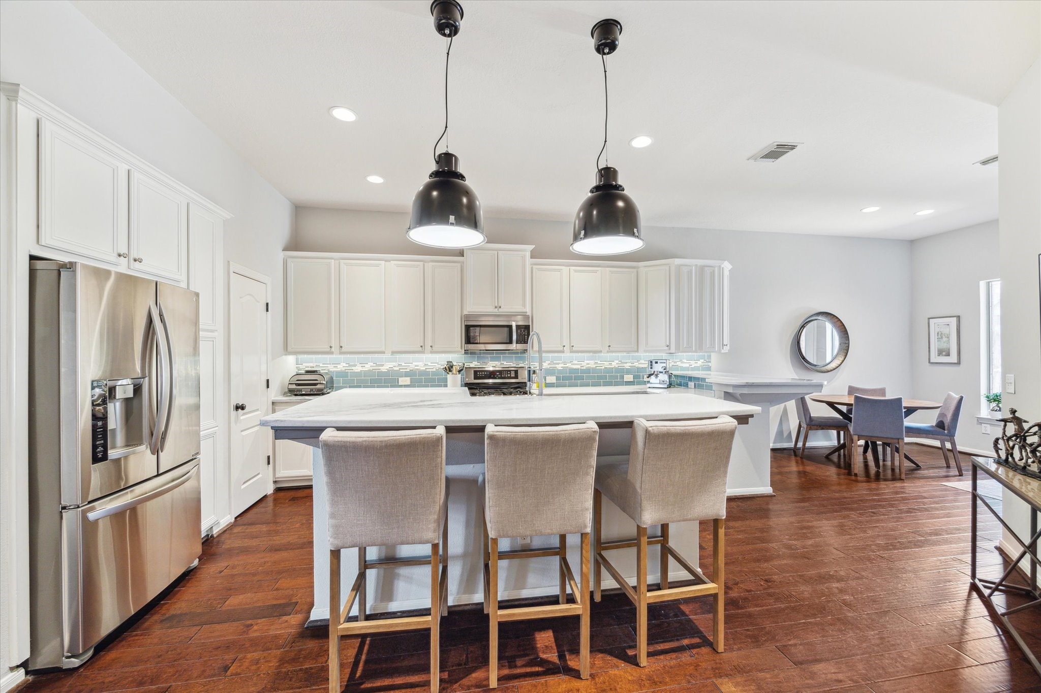3310 Spring Landing Lane Pearland, TX 77584 - Photo 2 of 32 Gorgeous updated kitchen with marble counters, island breakfast bar seating, pendant lighting, and bright cabinetry—made for entertaining.