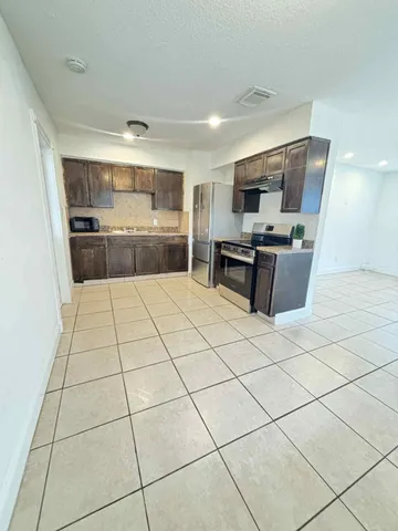 a large white kitchen with a large window and stainless steel appliances