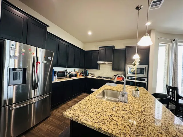 a kitchen with stainless steel appliances granite countertop a refrigerator stove microwave and sink