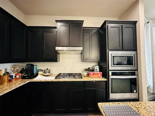 a kitchen with a refrigerator and a stove top oven