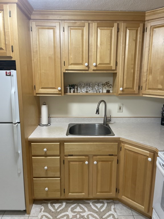 205 Great Road, Unit C8 Acton, MA 01720 - Photo 23 of 34 a kitchen with a cabinets and a refrigerator