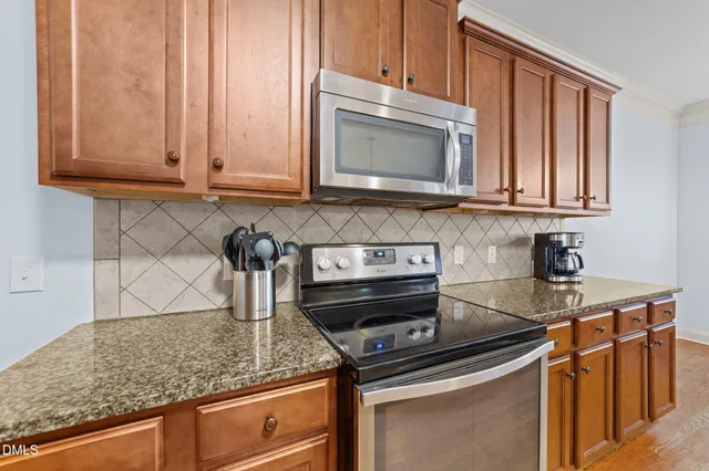 a kitchen with stainless steel appliances granite countertop a stove a sink a microwave a dining table and chairs with wooden floor