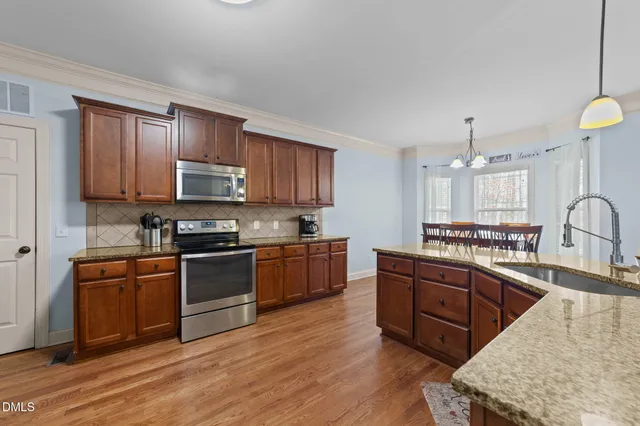 a kitchen with stainless steel appliances granite countertop a sink stove and microwave