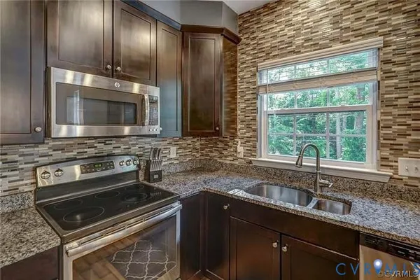 a kitchen with granite countertop a sink stove and refrigerator