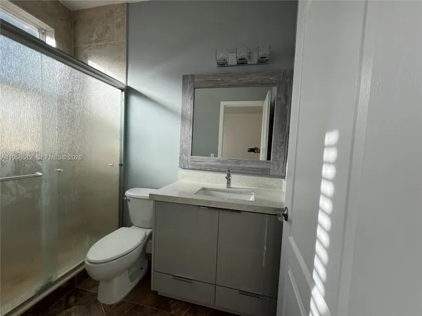 a bathroom with a granite countertop toilet a sink and mirror