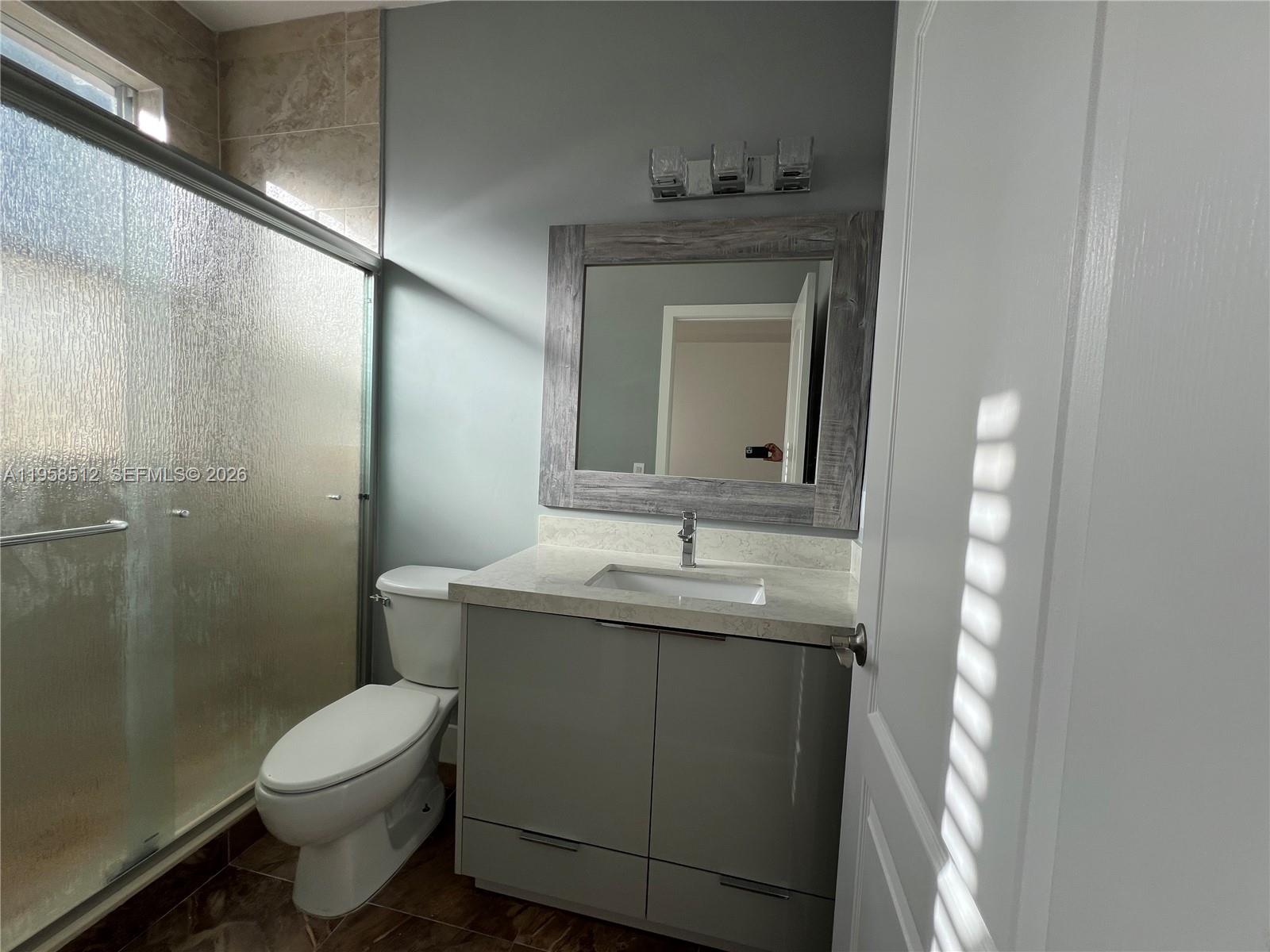 8001 West 36th Avenue, Unit 1 Hialeah, FL 33018 - Photo 34 of 48 a bathroom with a granite countertop toilet a sink and mirror