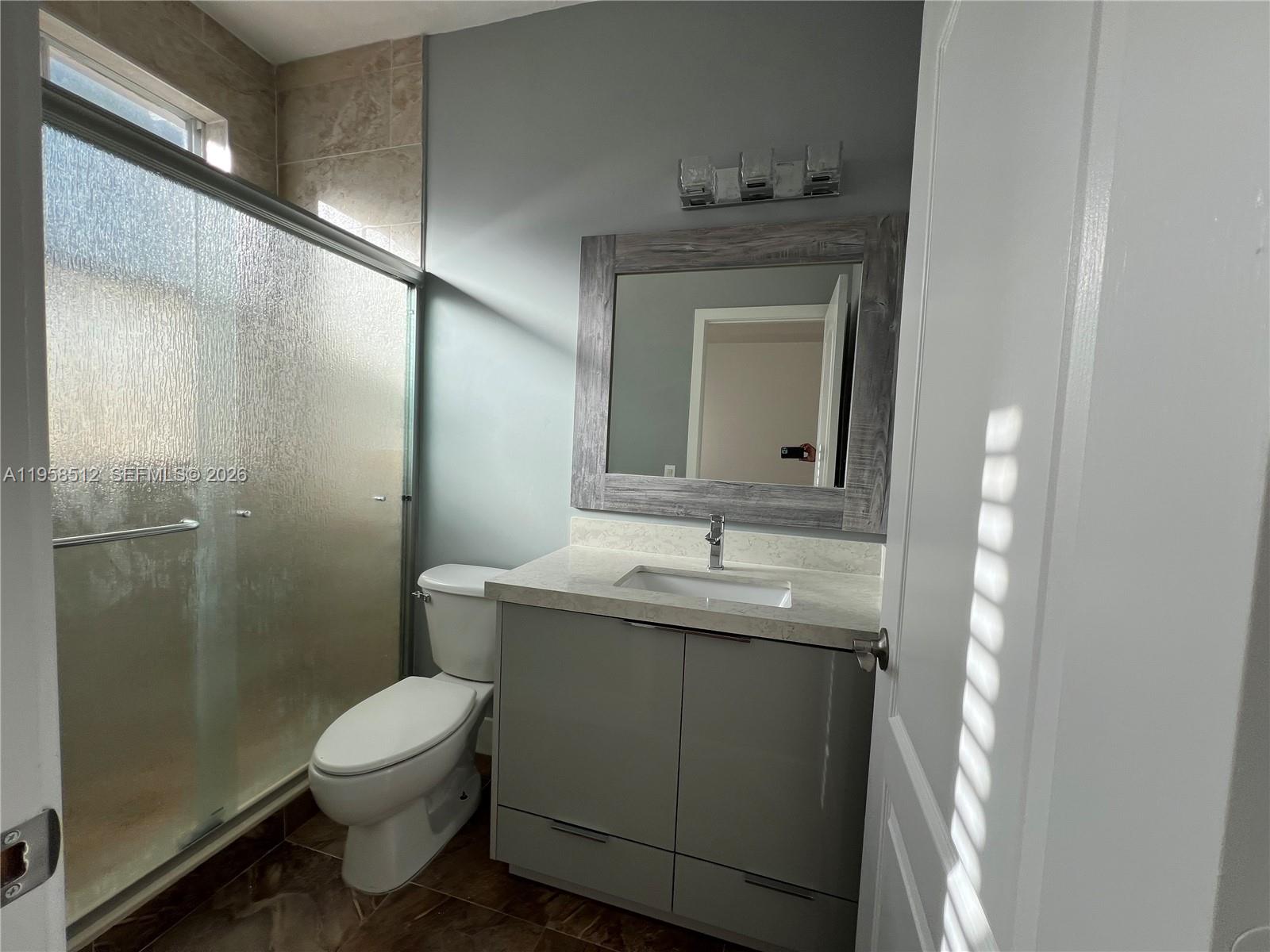 8001 West 36th Avenue, Unit 1 Hialeah, FL 33018 - Photo 35 of 48 a bathroom with a granite countertop toilet a sink and mirror