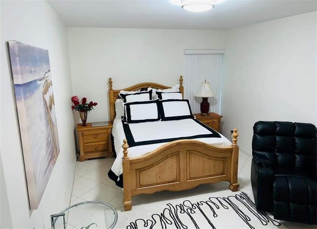 6574 Burning Wood Drive, Unit 101 Boca Raton, FL 33433 - Photo 5 of 25 a bedroom with a bed and wooden floor