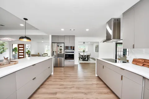 a large white kitchen with lots of counter space and stainless steel appliances