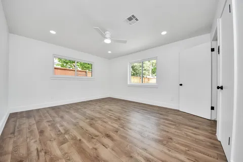 a view of an empty room with wooden floor and a window