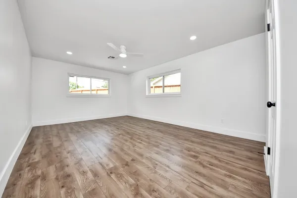 an empty room with wooden floor and windows