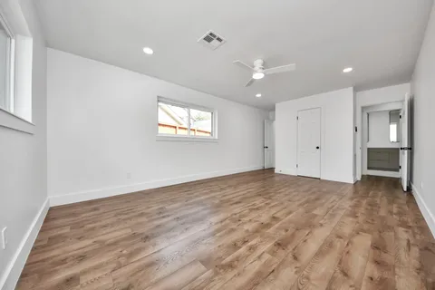 an empty room with chandelier fan and windows