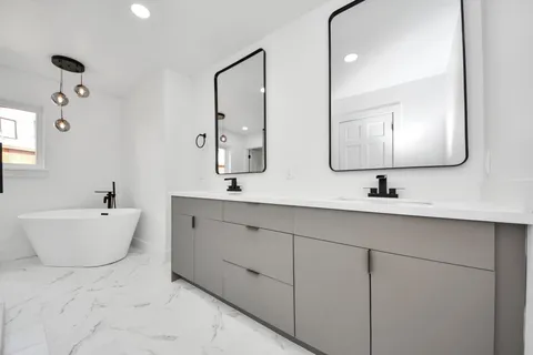 a bathroom with a double vanity sink mirror and bathtub