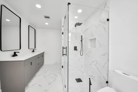 a bathroom with a double vanity sink mirror double and shower