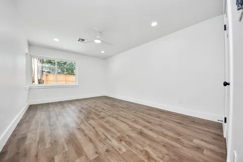 an empty room with wooden floor and windows