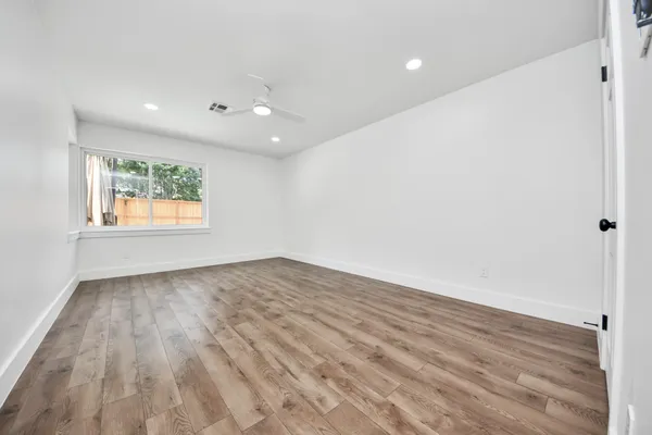 an empty room with wooden floor and windows