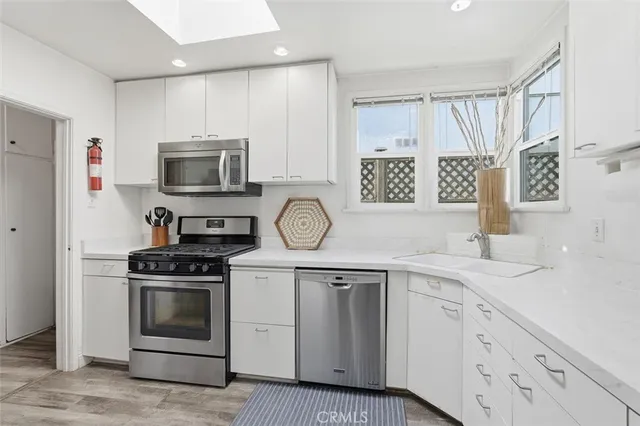a kitchen with white cabinets stainless steel appliances and sink
