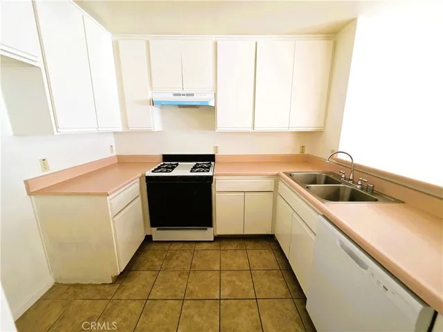 a utility room with a sink a stove top oven and cabinets