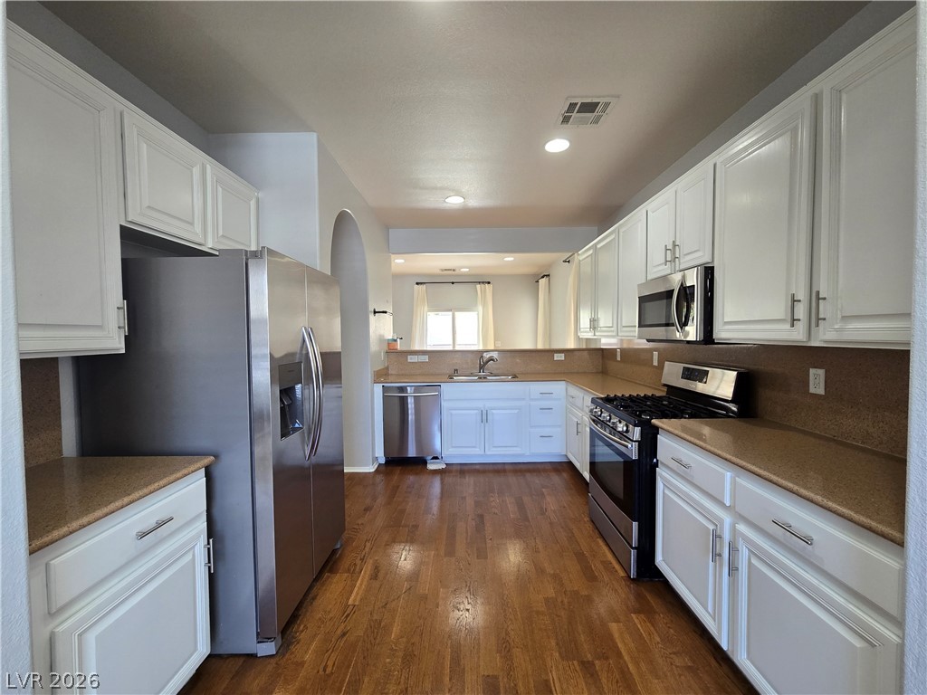 1049 Garnet Ridge Court Las Vegas, NV 89123 - Photo 12 of 39 Kitchen with stainless steel appliances, white cabinets, dark wood-type flooring, recessed lighting, and arched walkways