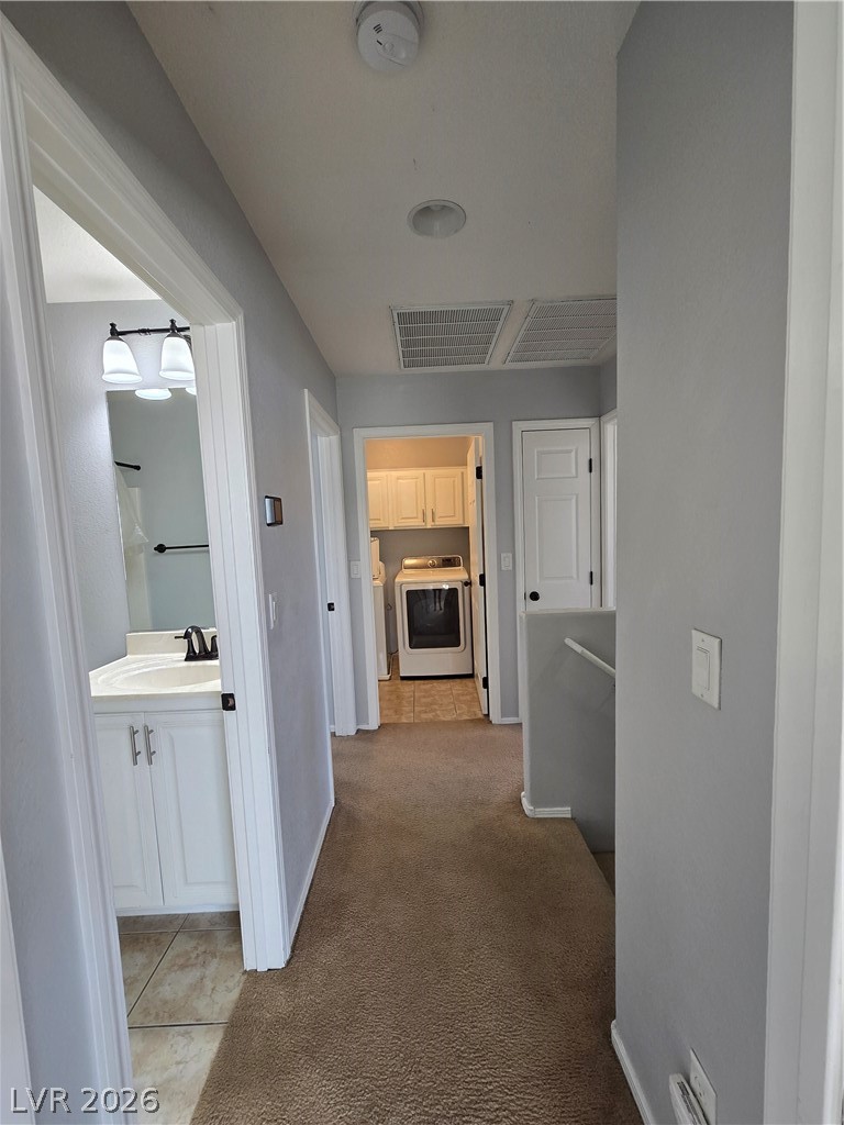 1049 Garnet Ridge Court Las Vegas, NV 89123 - Photo 21 of 39 Hallway with light colored carpet, light tile patterned floors, an upstairs landing, and washing machine and clothes dryer