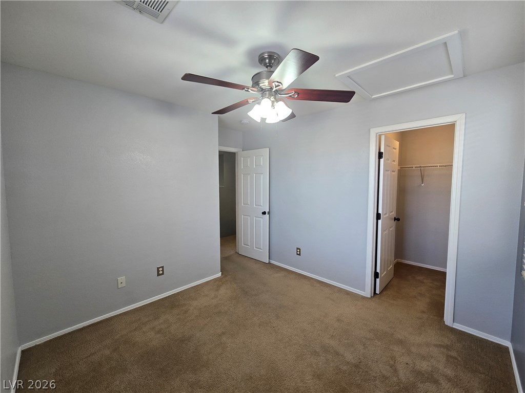 1049 Garnet Ridge Court Las Vegas, NV 89123 - Photo 35 of 39 Unfurnished bedroom with a walk in closet, dark carpet, and a ceiling fan