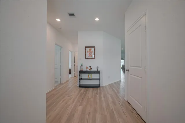a view of a hallway with wooden floor and a bathroom