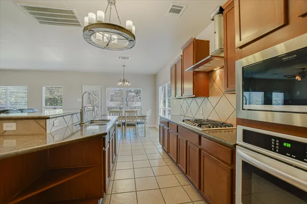 a kitchen with stainless steel appliances granite countertop a sink a stove oven a counter space and cabinets